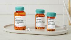 Three Amazon Pharmacy prescription medication pill bottles on a white bathroom countertop