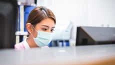 Nurse in mask using a computer.