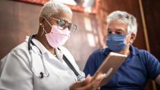 A doctor talking to a patient while holding a tablet.