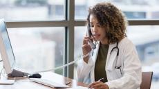 A doctor talking on a phone while taking notes.