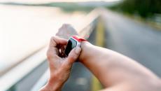 Person adjusting their fitness wearable while exercising outside