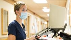 Healthcare worker in mask working on a laptop