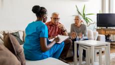 Two people sitting on a couch talking to a healthcare provider who is sitting on a different couch