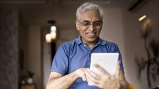 Person wearing a blue shirt and holding a tablet in the living room of a home