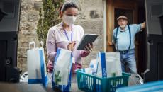 A man waiting in a doorway as a woman delivers medications