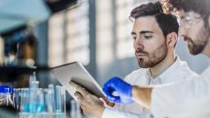 Two scientists in a lab looking at a tablet