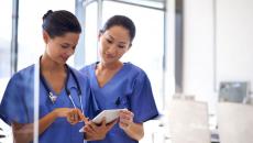 Two healthcare providers looking at a tablet