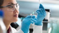 A researcher holding an injection and a vial of drug