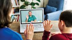 Two people waving at a healthcare provider on a computer