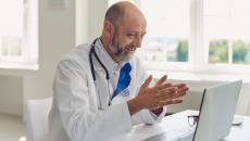 A doctor conducting a virtual consultation with a patient using a laptop