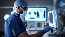 Healthcare provider in scrubs standing in front of an imaging screen