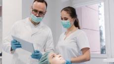 A dentist and their assistant checking a patient's record from a digital tablet