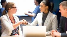 Businesspeople shaking hands in front of a laptop