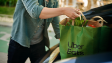 Person putting a bag of groceries from Uber Eats in a car's trunk